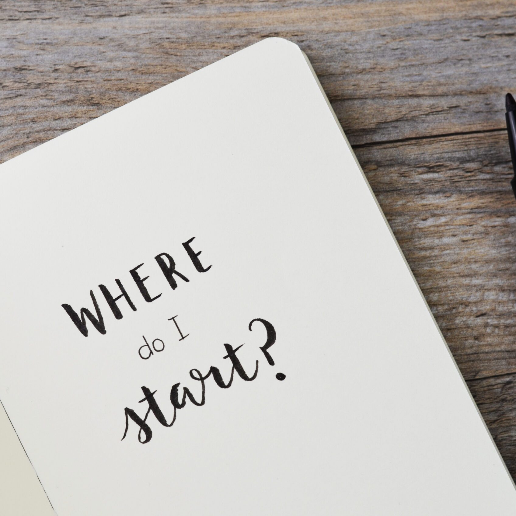 WHERE DO I START? hand lettering in notebook with pen on wooden background